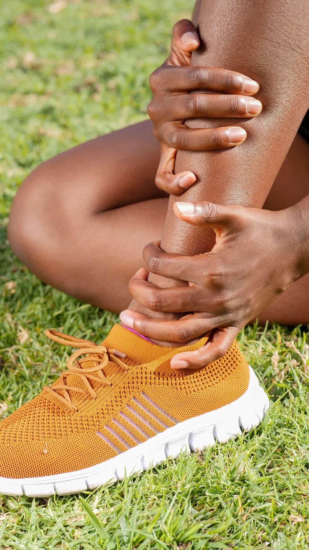 A person supporting an injured ankle outdoors