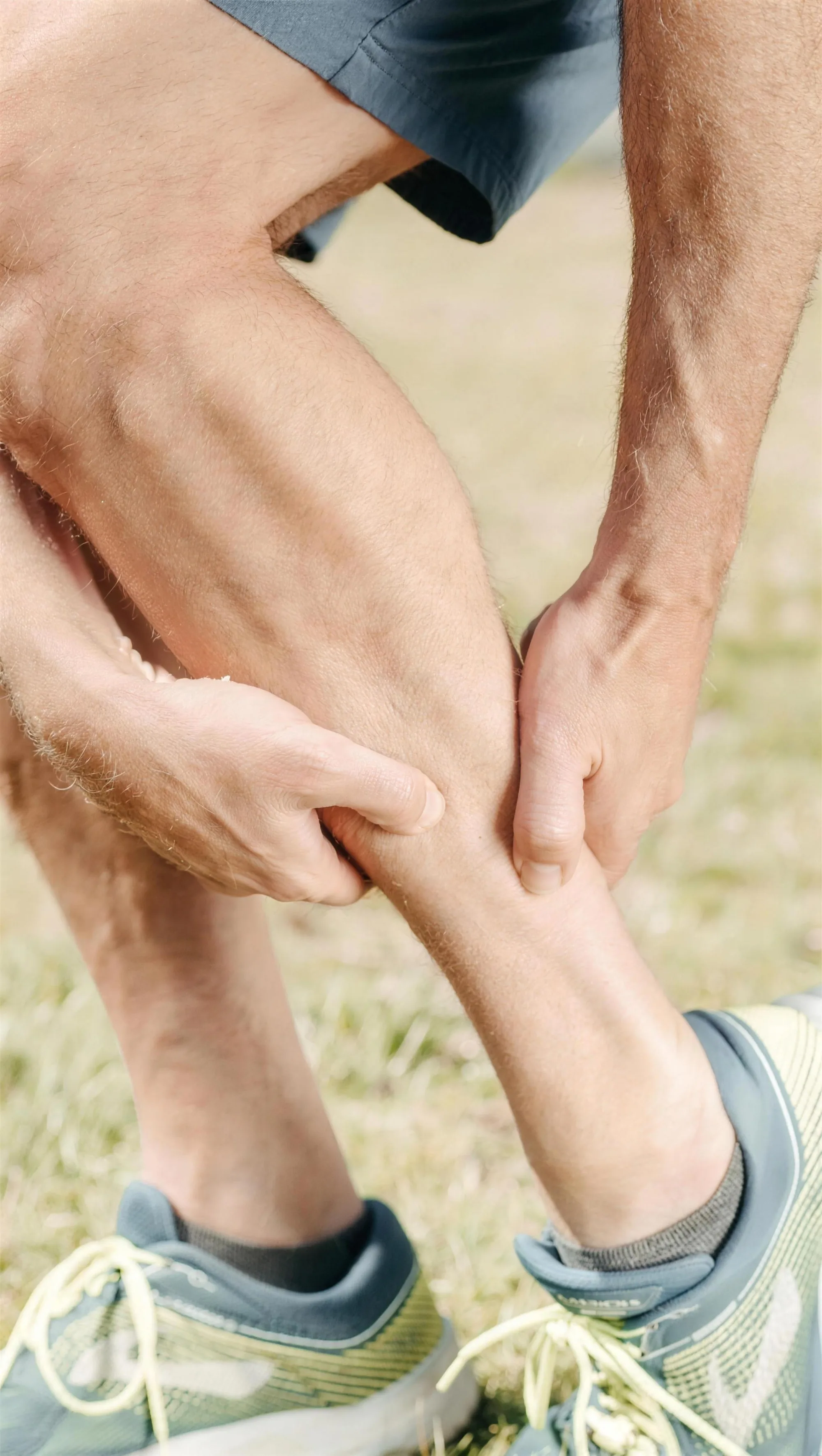 A person holding a painful calf after exercise